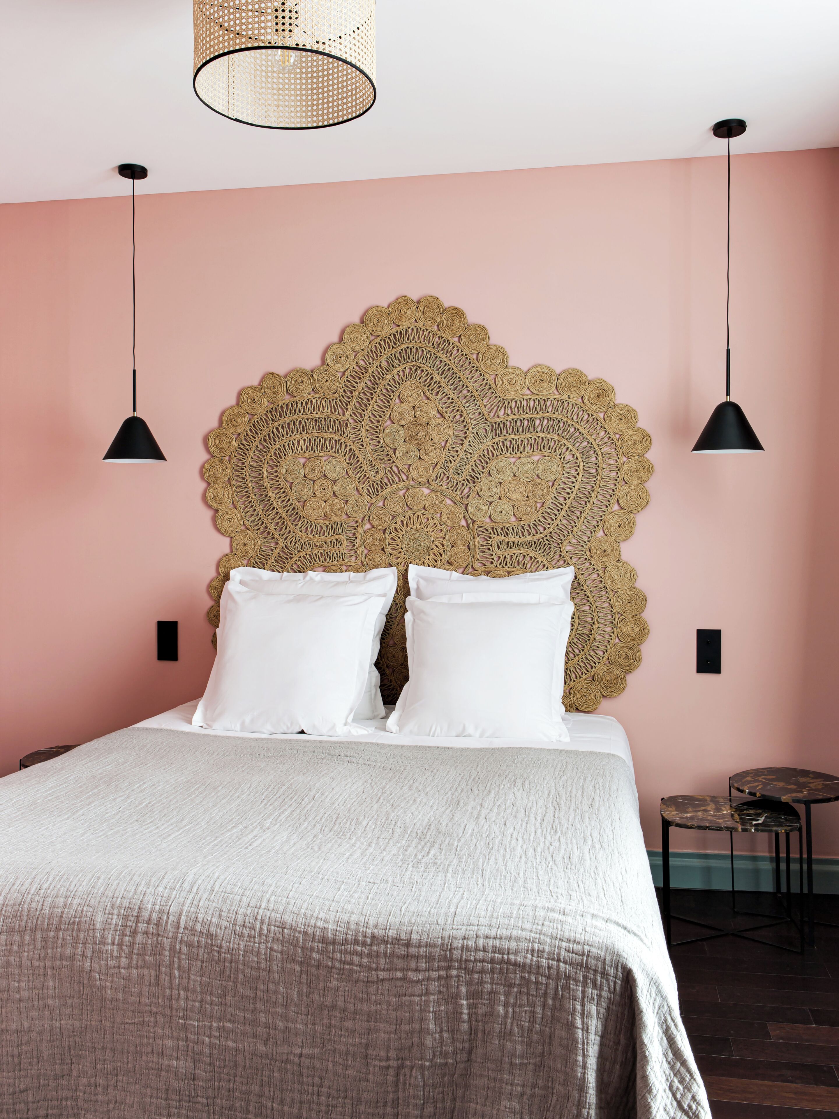 A bed with a textured headboard, two bedside lamps, and a small table with chairs.