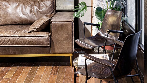 A modern interior with a leather sofa, two chairs, a potted plant, and a large window. - New Hotel Le Quai - Vieux Port (Marseille)