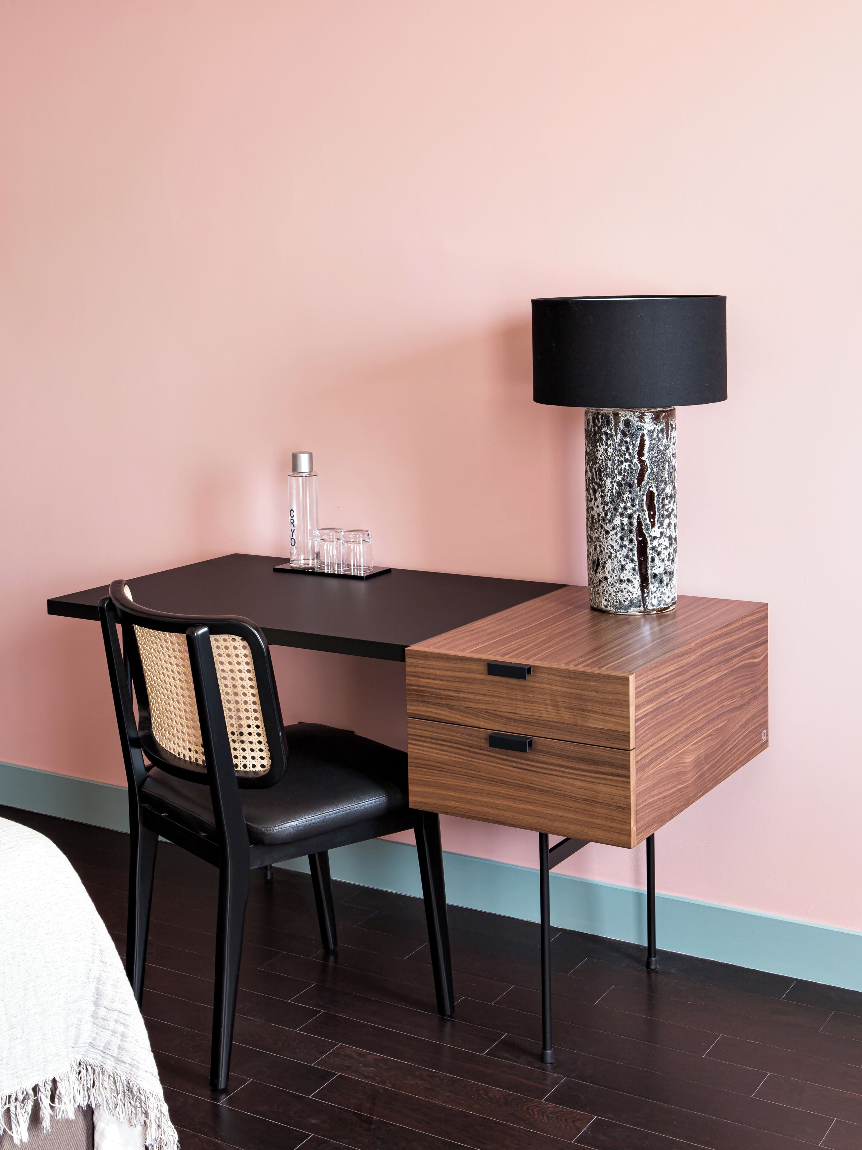 Une pièce comprenant un bureau, une chaise, une lampe et une bouteille d’eau.