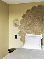 A bed with a textured headboard, a white pillow, and a grey blanket.