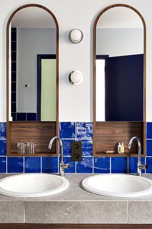 Un baño con dos lavamanos, un espejo y un perchero para toallas.
