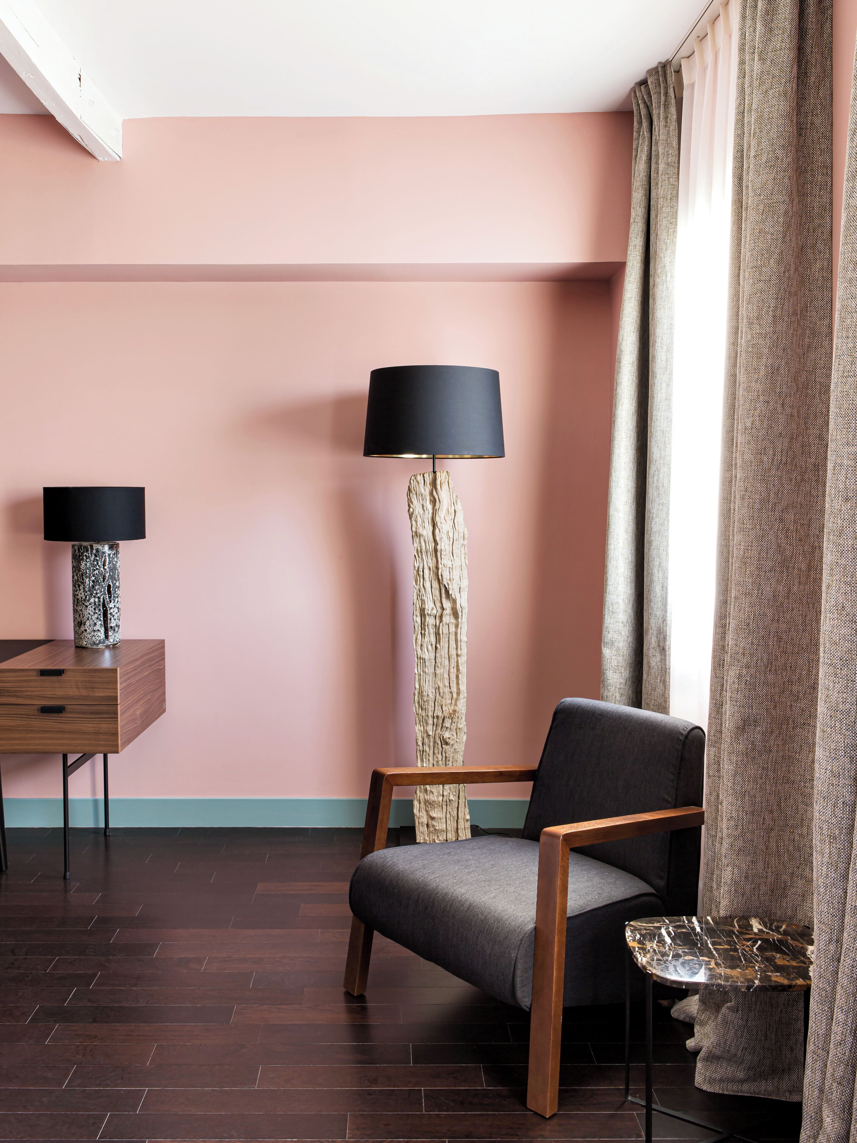 Una habitación con un escritorio de madera, una silla, una lámpara de pie y una mesa.