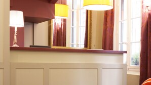 A hotel room with a large mirror, a yellow lamp, and a red accent wall.
