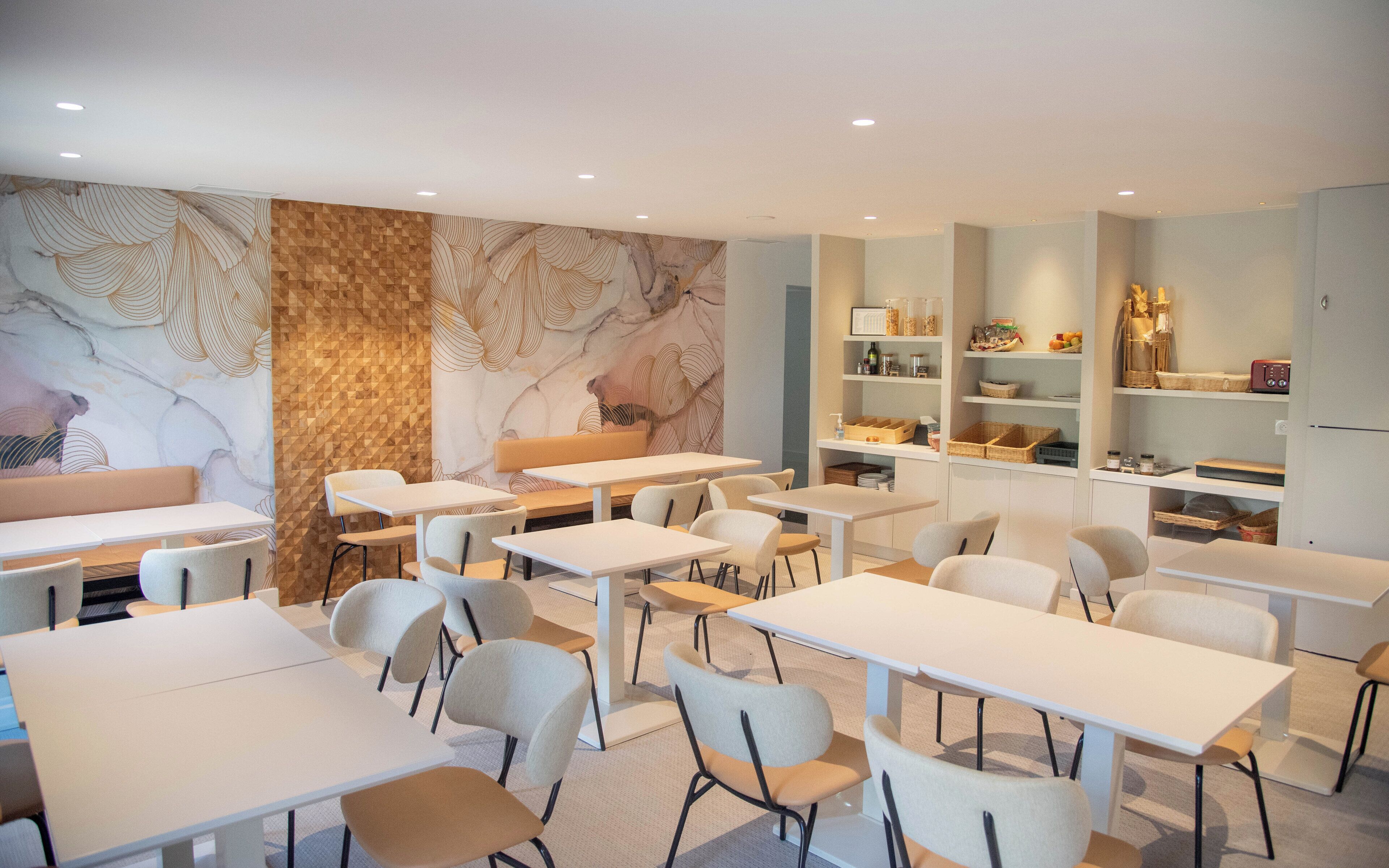 A modern dining area with white tables and chairs, a patterned wall, and shelves with kitchen items.