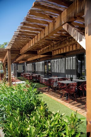 Une terrasse extérieure dotée d’une pergola en bois, de tables et de chaises.