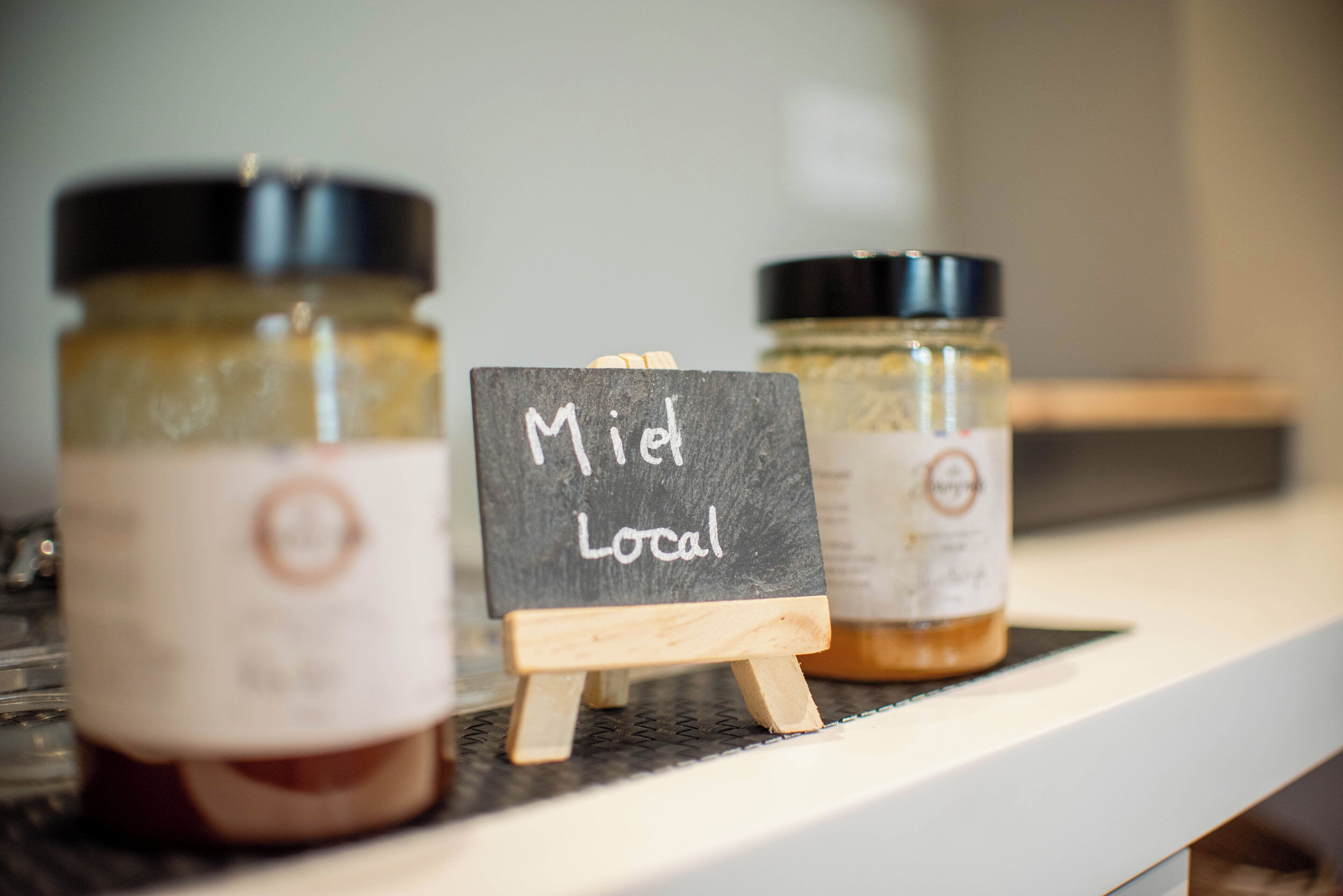 Three jars of jam on a shelf with a sign that reads "Miet Local".