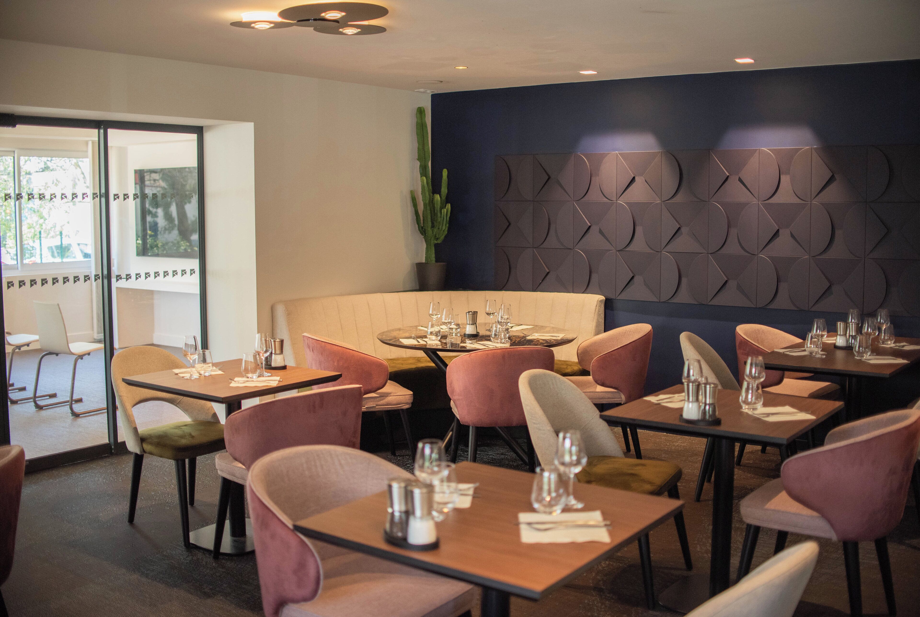 Ein Restaurant mit runden Tischen, gepolsterten Stühlen und einer Sukkulente.