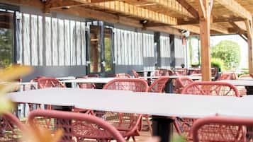 An outdoor seating area with wooden beams and red chairs.