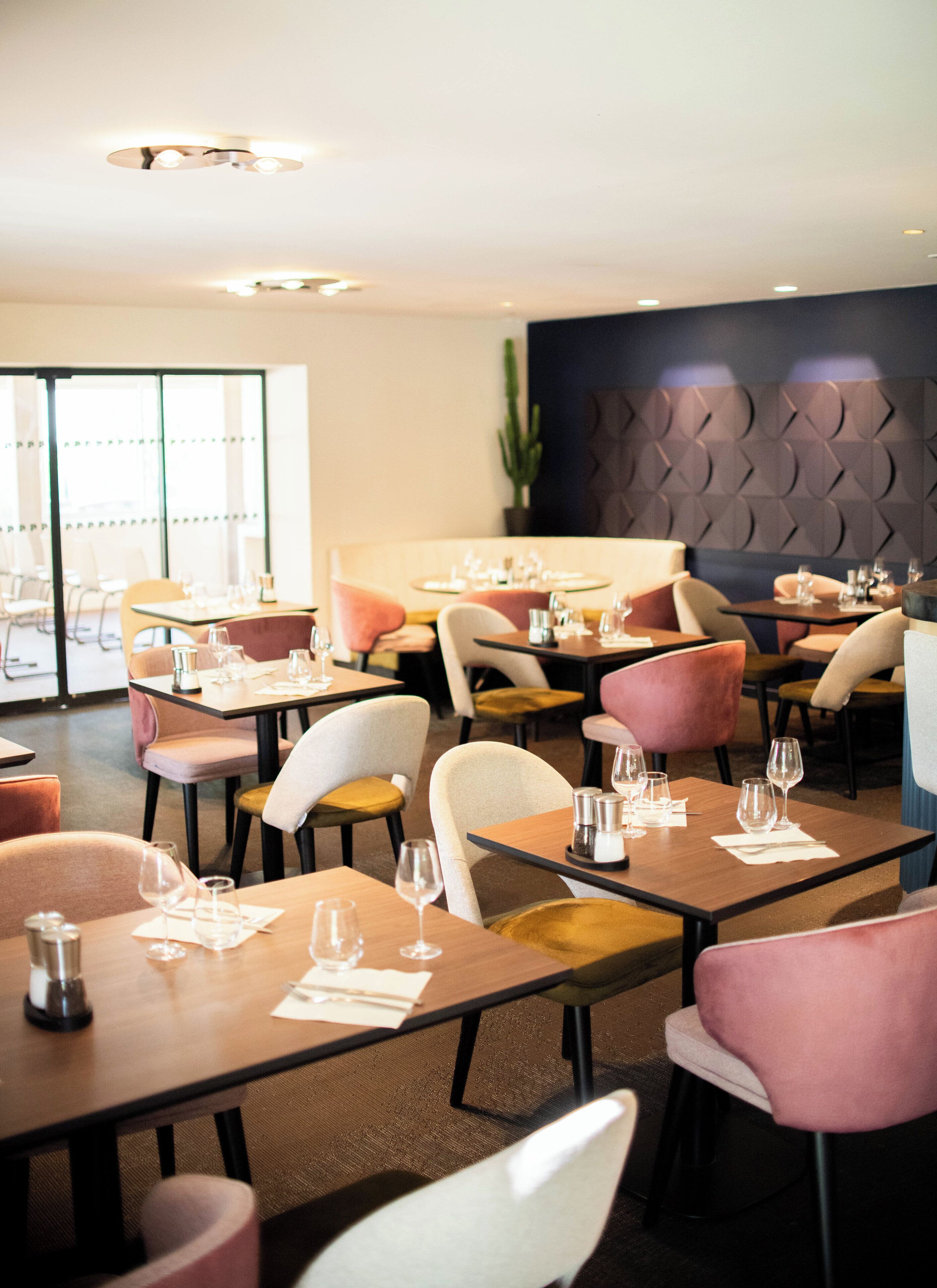 A restaurant with tables set for dining, chairs, and a modern interior design.