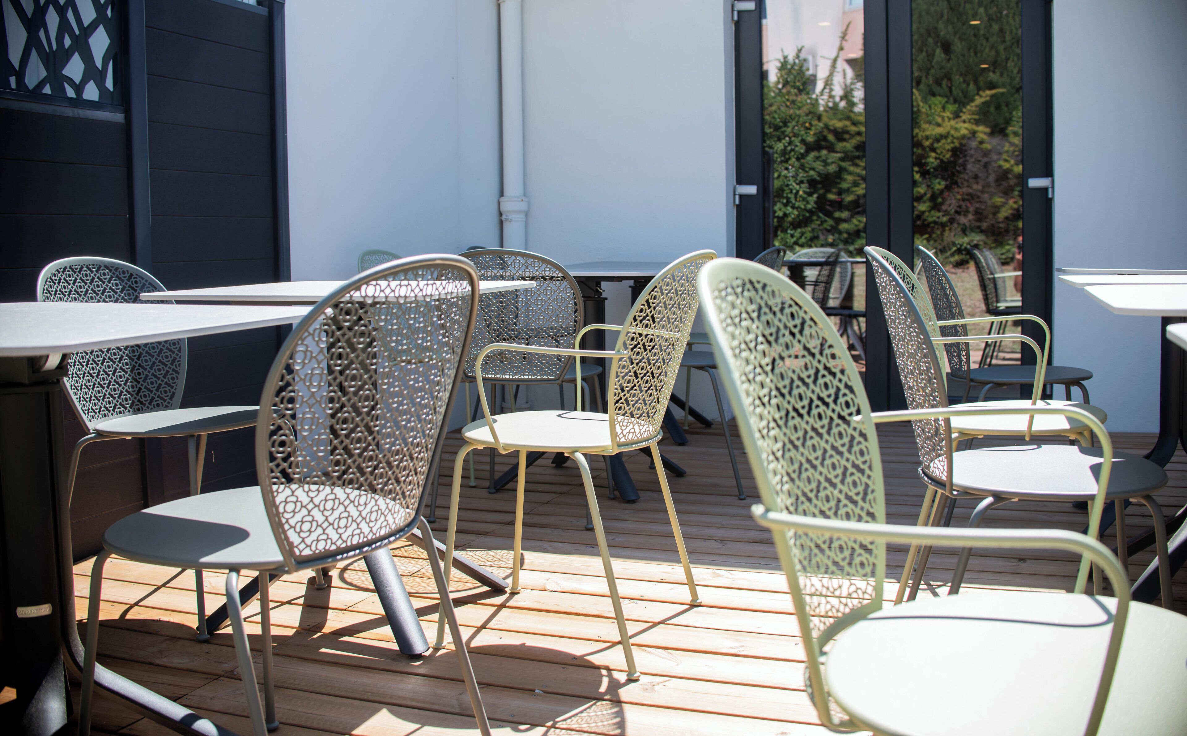 Outdoor patio furniture with metal chairs and tables, arranged on a wooden deck.