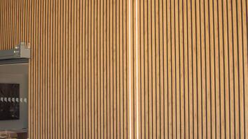 A room with vertical wooden paneling and a vent on the wall.