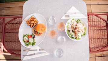 A table with a burger, fries, salad, and two glasses of water.
