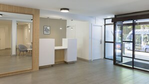Un área de recepción con un mostrador de madera, una silla y un espejo grande.