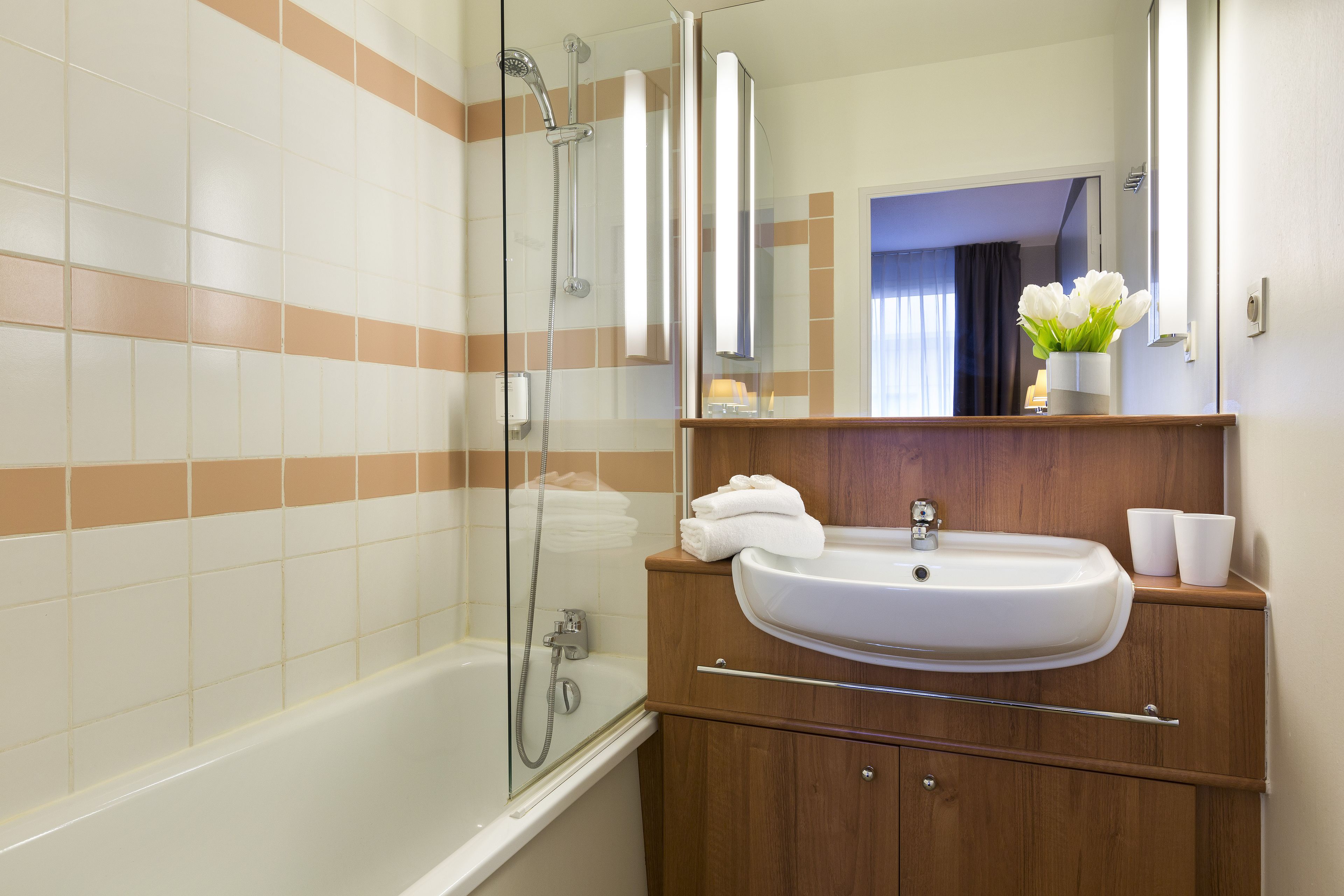 A bathroom with a bathtub, a sink, and a mirror.