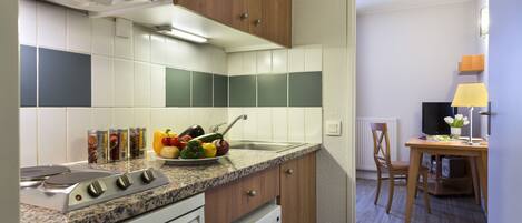 A modern kitchen with a granite countertop, white appliances, and a dining area with a wooden table and chairs.