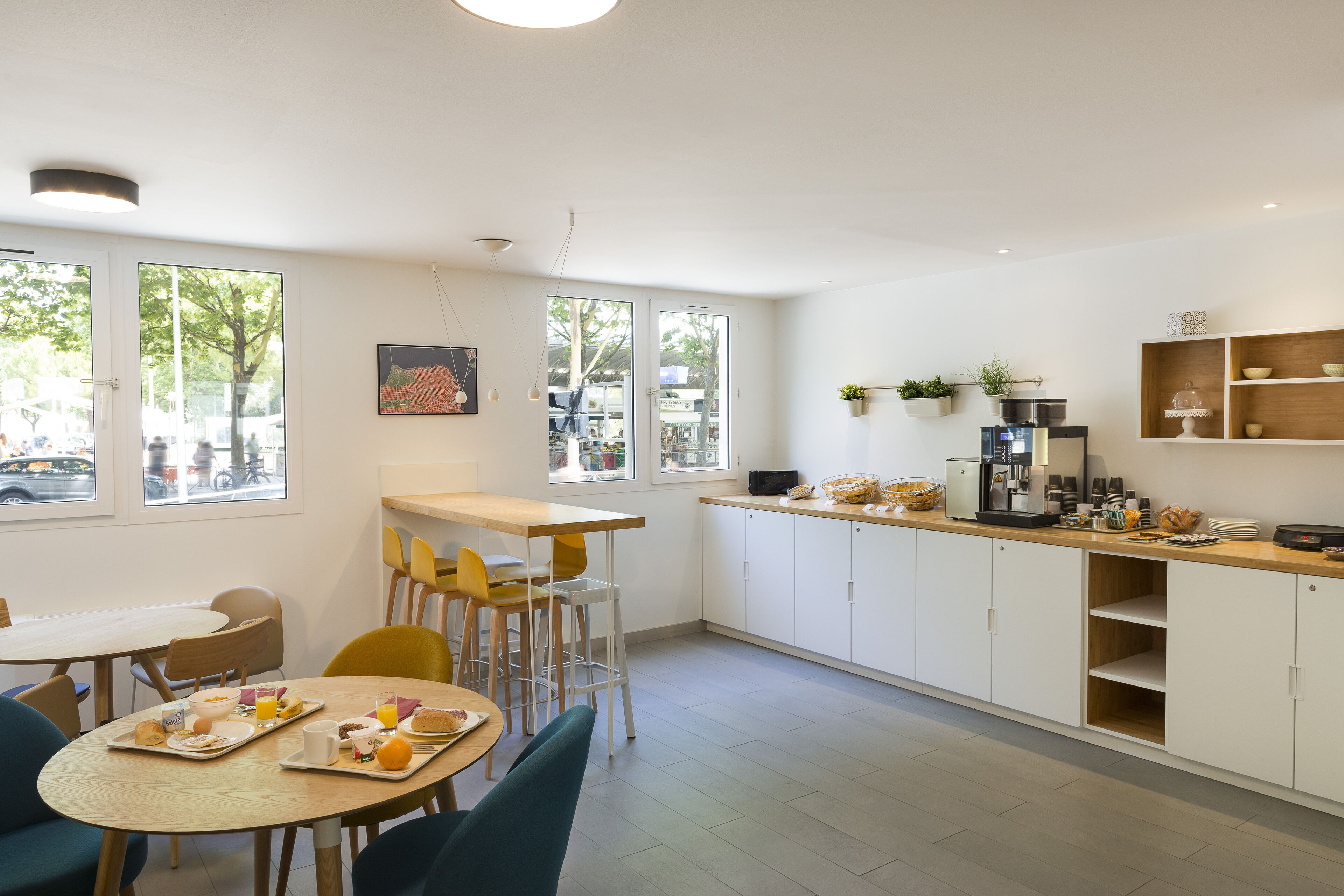 Una cocina moderna con armarios blancos, encimera de madera y comedor con sillas y una mesa preparada para el desayuno.