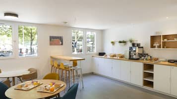 Una cocina moderna con armarios blancos, encimera de madera y comedor con sillas y una mesa preparada para el desayuno.
