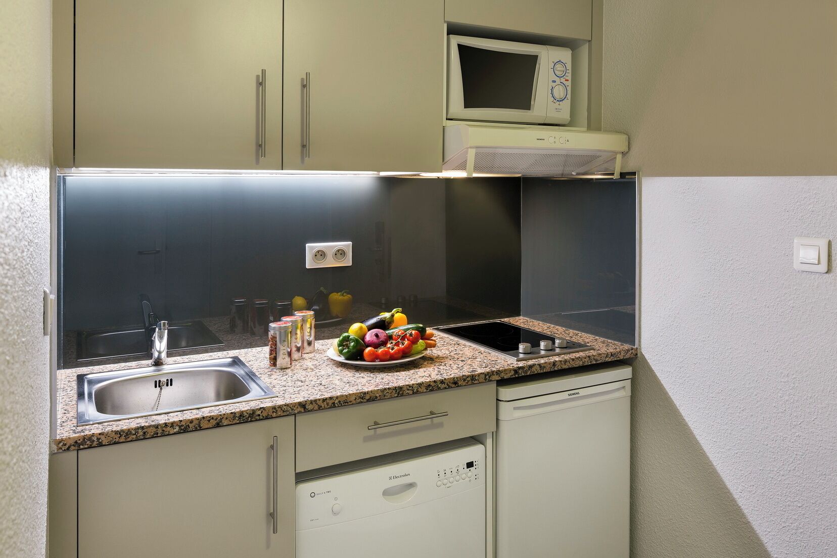 Una cocina compacta con microondas integrado, un lavabo y lavavajillas.