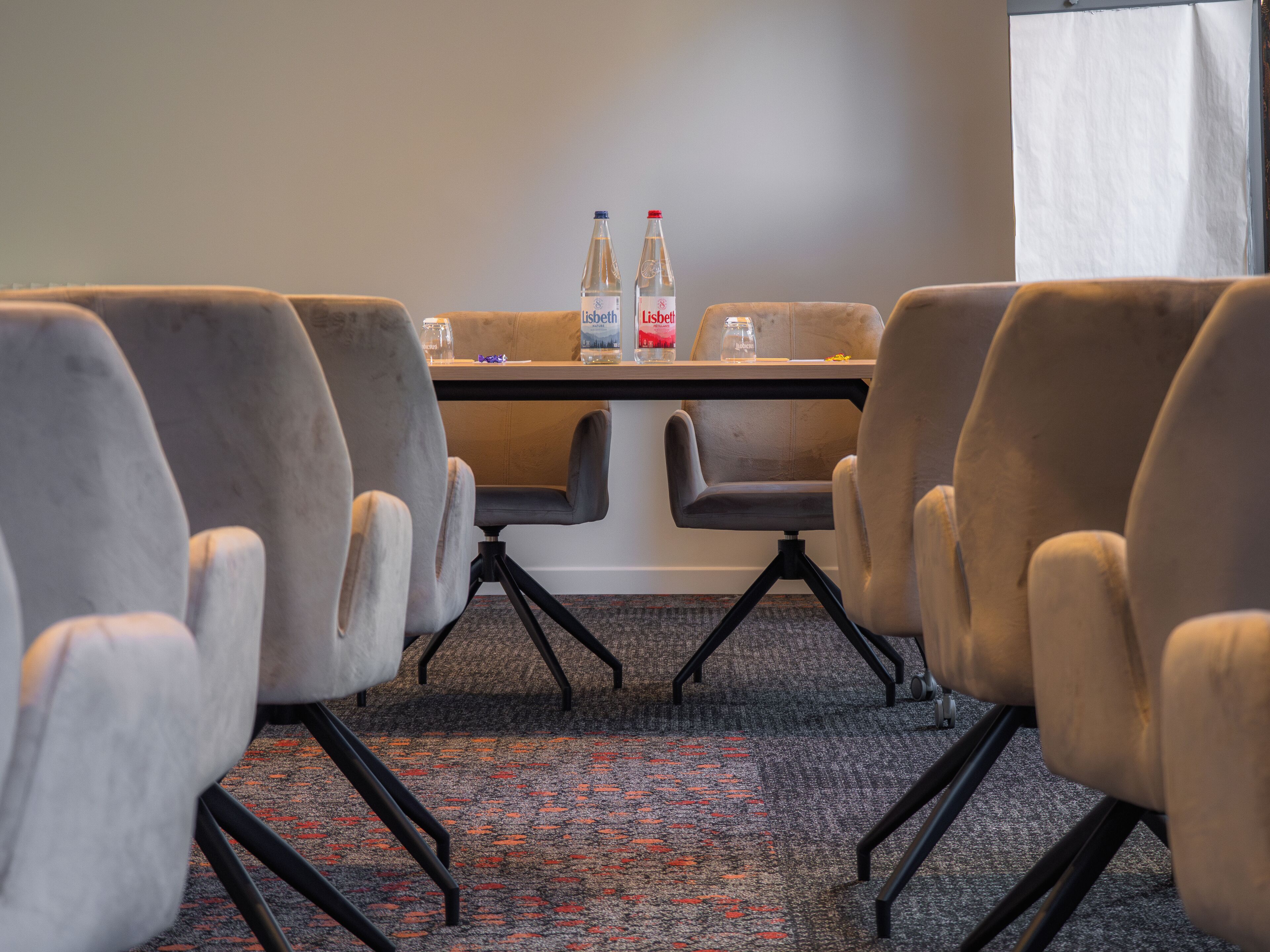 Une salle de conférence équipée d’une table, de chaises et de deux bouteilles d’eau.