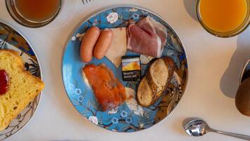 Een ontbijttafel met eten op een bord, een glas jus d'orange en een glas thee.