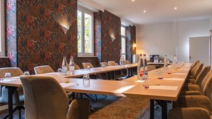 Un salón de conferencias con una larga mesa, sillas y botellas de agua.