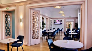 Un comedor moderno con mesas redondas y sillas azules, suelo de madera y paneles decorativos en la pared.