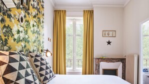 A hotel room with a bed, a window with curtains, a fireplace, and a wall with a star decoration. - Hotel Stanley by HappyCulture (Nancy)