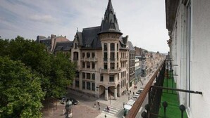 A historic building with a prominent tower and multiple windows, situated along a busy street with pedestrians and vehicles. - Hotel Stanley by HappyCulture (Nancy)