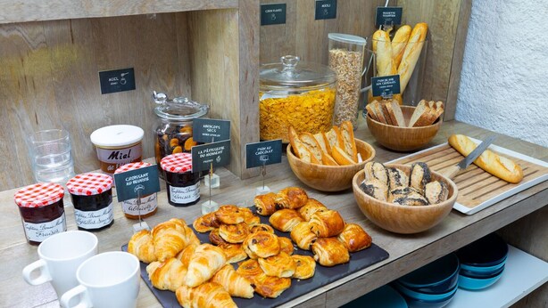 A breakfast buffet with various pastries, bread, and condiments. - Hotel Stanley by HappyCulture (Nancy)
