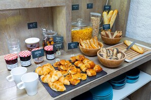 Un bufé de desayuno con diversos pasteles, pan y salsas.
