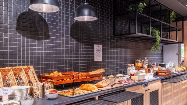 A buffet setup with various food items, including bread, pastries, and condiments. - Ibis Nantes Nord Treillières (Treillieres)