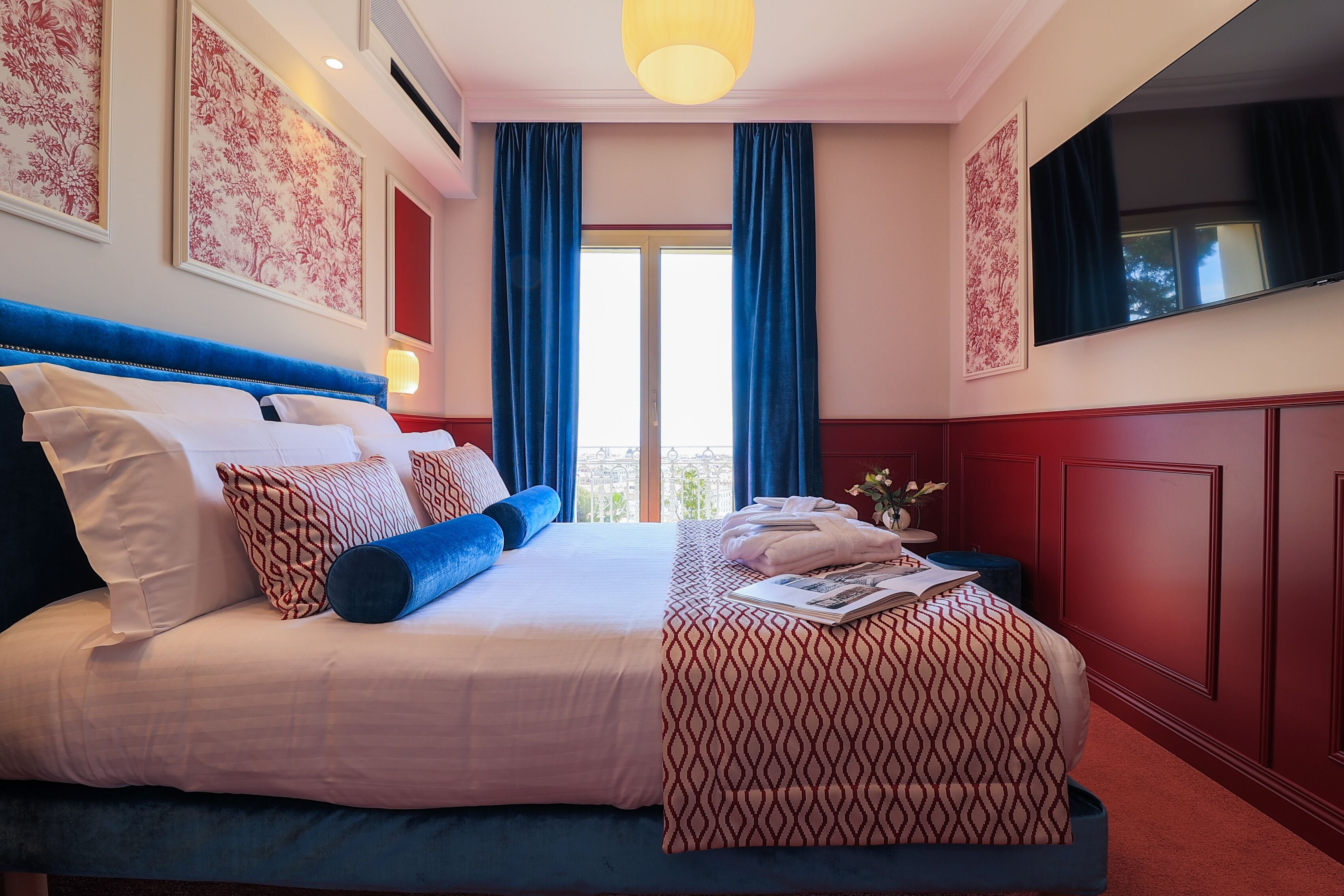 A hotel room with a large bed, a flat-screen TV, and a balcony view.