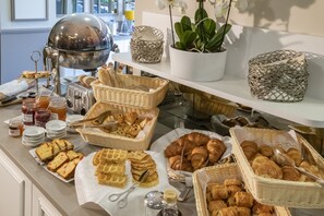 Un bufé con panes, pasteles y salsas diversas.