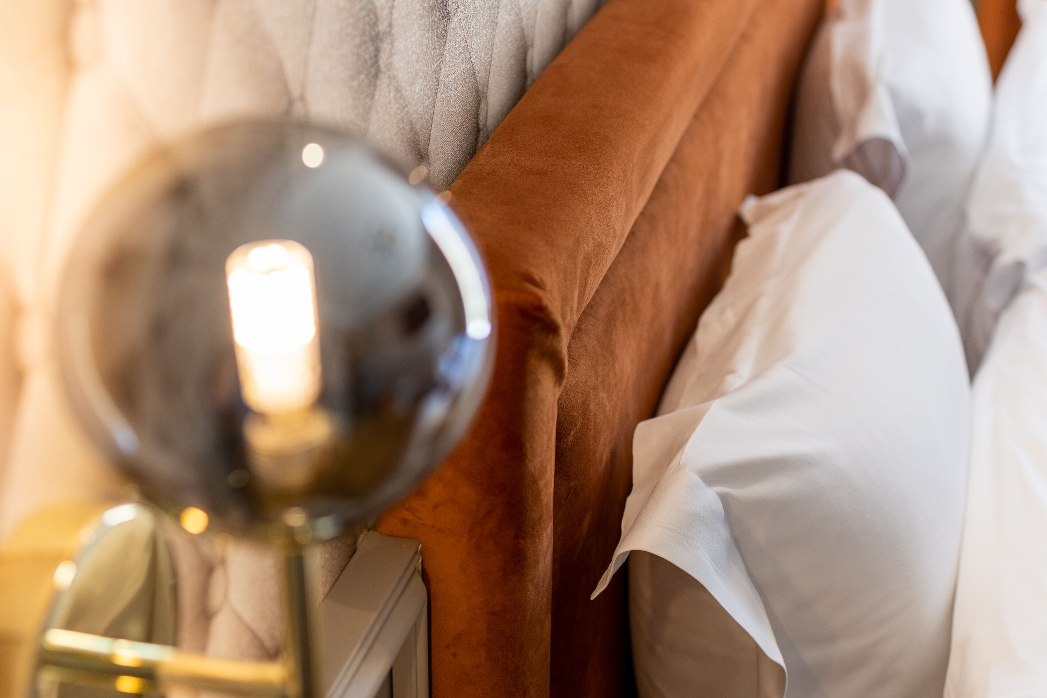 Een close-up van een bed met een bruin hoofdeinde en witte kussens.