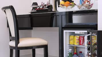 Una cuina moderna amb un taulell negre, una cadira blanca i un mini-frigorífic ple de begudes.