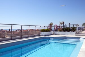 Una piscina al aire libre de temporada, sombrillas