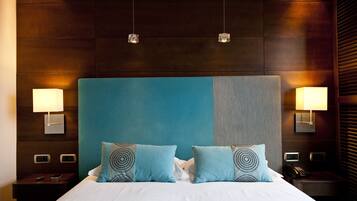 Una habitación de hotel con una cama grande, dos lámparas de noche y una mesita de noche con un teléfono.