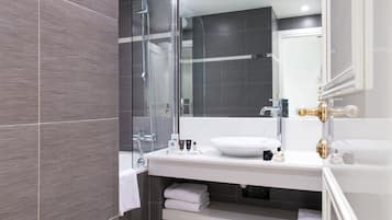 Une salle de bain moderne avec une douche à parois de verre, un lavabo blanc et un grand miroir.