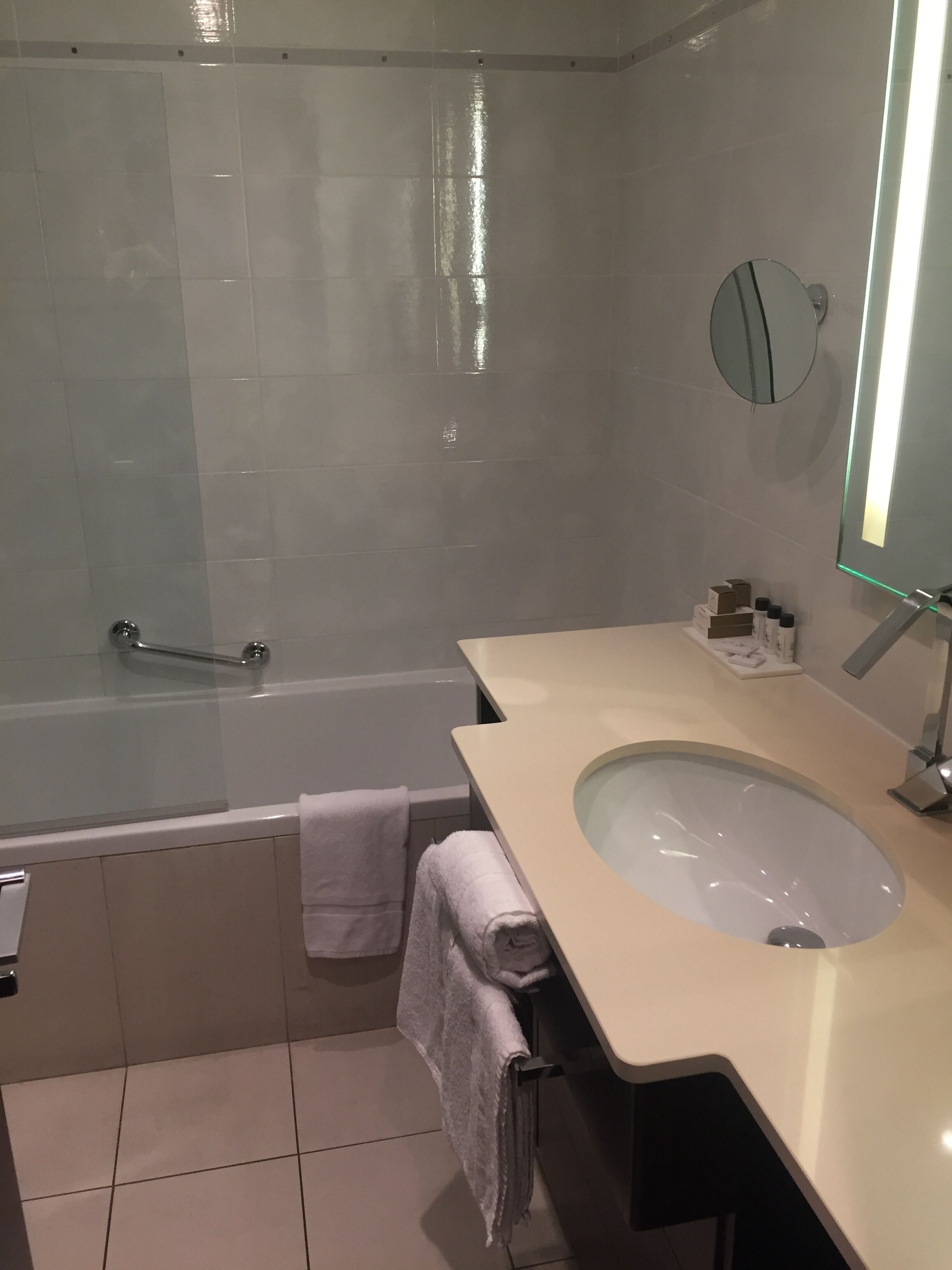 Une salle de bain moderne avec une baignoire, un lavabo avec un miroir et un porte-serviettes.