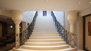 A grand staircase with a black wrought iron railing, leading to a high ceiling with recessed lighting. - Hôtel Aston La Scala (Nice)