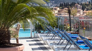 A poolside area with lounge chairs and a palm tree. - Hôtel Aston La Scala (Nice)