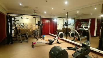 Un gimnasio con diversos equipos de ejercicio, como una máquina de remo, elíptica y bicicleta estática.
