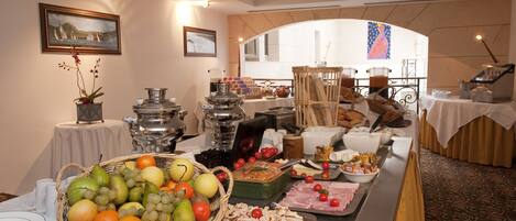 A buffet setup with various food items and a decorative orchid.