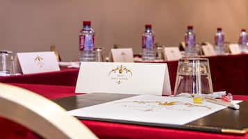 Une table de conférence avec des cartes de nom, des bouteilles d’eau et un menu posé sur une nappe rouge.