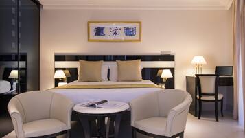 Habitación de hotel con cama, dos sillones, una mesita y un escritorio con silla.