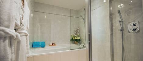 A modern bathroom with a glass-enclosed shower, a bathtub, and a vanity area.