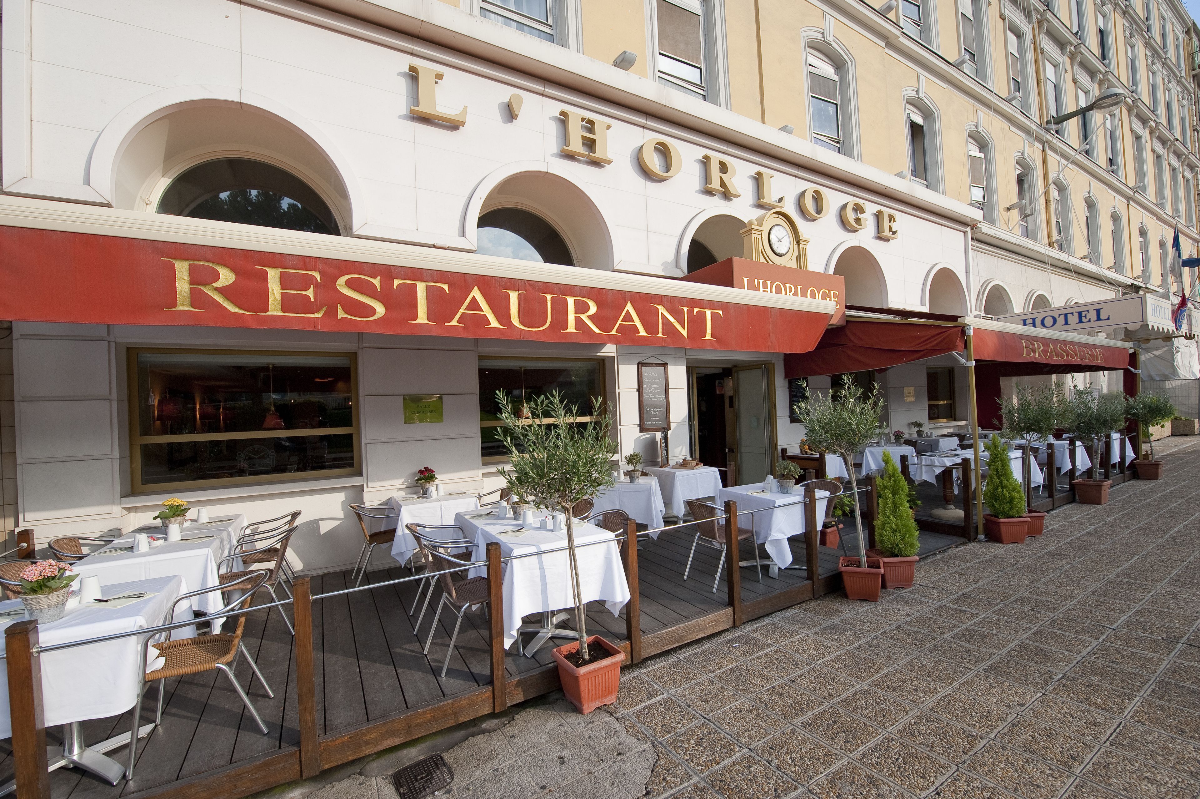 Un restaurante con terraza, mesas, sillas y macetas.