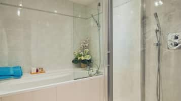 A modern bathroom with a glass-enclosed shower, a bathtub, and a toilet.