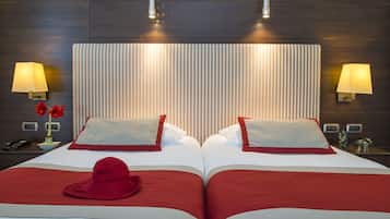 A hotel room with a large bed, two bedside lamps, a telephone, and a decorative vase with flowers.
