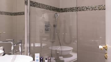 A modern bathroom with a glass-enclosed shower, a white sink, and a vanity with toiletries.